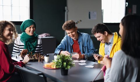 5 happy people sitting around a desk playing games