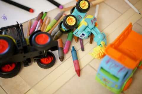 Childs drawings on paper and colourful pencils on a table and some plastic toys