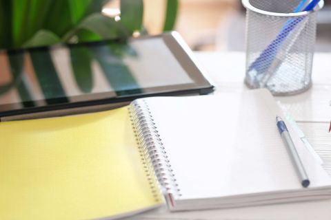 image of a tablet computer and opened paper notepad