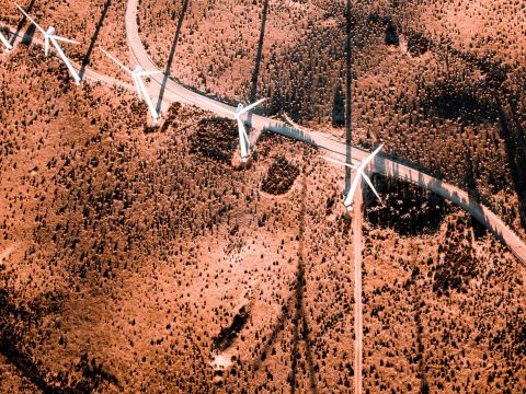 image from the air looking down on a red ground and a row of wind turbines
