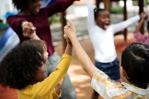 Image of a group of diverse kindergarten students hands up