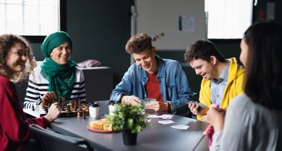 5 happy people sitting around a desk playing games