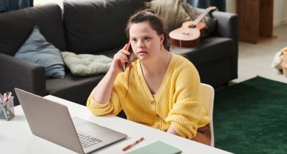 Person sitting at a desk in front of computer talking on a mobile phone