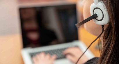 Women with headset on, working on a laptop