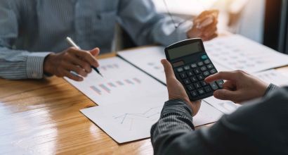 Businessman pointing at a graph with a pen, another using a calcuator