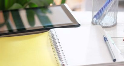 image of a tablet computer and opened paper notepad