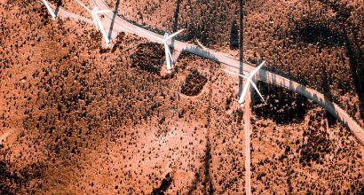 image from the air looking down on a red ground and a row of wind turbines